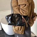 Grande borsa tote nera lucida con ciondolo a forma di orso e nappa indossata dal modello - Nero