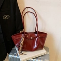 Borsa tote rosso scuro lucida con nappe e tracolla su una valigia argentata - Borgogna