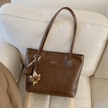 Detail of a dark brown PU leather tote bag with a star and bear charm on a sofa - Brown with Pendant
