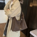 Deep brown matte leather tote bag with gold bar and tassel, shown on model - With Charm / Brown