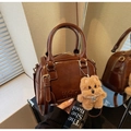 Detailed macro view of retro brown oil-wax leather handbag with dog plush charm and pearl - With Charm / Brown
