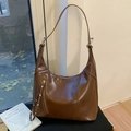 Vista dettagliata di una borsa hobo a mezzaluna marrone con cerniere decorative e nappe - Marrone