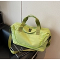 Close-up of avocado green travel bag with durable straps and brand logo on a sofa - Green