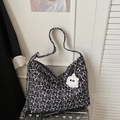 Detailed close-up of large floral tote bag with plush charm on a silver suitcase - Black