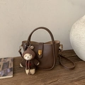 Close-up of brown pebbled leather handbag with gold clasp and cute bear charm - With Pendant / Brown