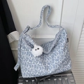 Light blue floral shoulder bag with plush charm on a silver suitcase for daily commuting - Blue