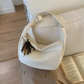 Detail van crèmekleurige tas met litchi-textuur, verstelbare riem en kwastje van gekleurde houten kralen - Wit