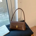 Detail der matten braunen Schultertasche mit elegantem goldenen ovalen Metallschloss - Karamell