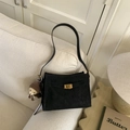 Detail of black matte bucket bag featuring a gold turn-lock and cute bear charm accessory - With Charm / Black