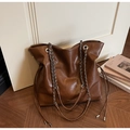 Detailed view of dark brown tote bag with silver chain strap and leather texture - Brown