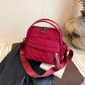 Macro shot of red quilted nylon handbag featuring diamond stitching and comfort strap - Red