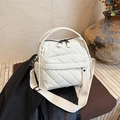 Close-up of white quilted tote bag featuring wide strap and dual zipper detail - White