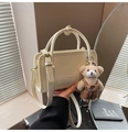 Details einer cremeweißen Handtasche mit Plüschbären-Anhänger und feinem Schulterriemen - Mit Anhänger / Weiß