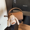 Brown leather cylinder crossbody bag with a plush bunny charm and adjustable strap - With Charm / Brown