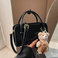 Minimalistische schwarze Lackleder-Handtasche mit Teddybär-Anhänger und Schultergurt - Mit Anhänger / Schwarz