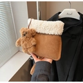 Detail der braunen Wildleder-Eimertasche mit weißem Lammfellbesatz und Bären-Anhänger - Cremeweiß Mit Anhänger