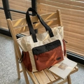 Borsa tote a contrasto tricolore panna e rosso, presentata su una sedia di legno - Rosso