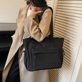 Black nylon tote bag with large capacity and drawstring details shown on a model - Black