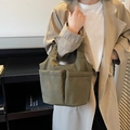 Olive green nylon tote bag with multi-pocket utility design shown on a female model - Green