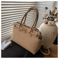 Detail of beige lychee grain tote bag with metal buckle in elegant sunlit scene - Khaki