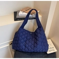 Detail of dark blue quilted tote bag with magnetic metal clasp and padded shoulder strap - Blue