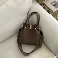 Detail of dark brown pebble leather bucket bag with wide woven strap and gold hardware - Coffee