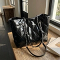 Grand sac cabas en cuir matelassé noir avec bandoulière chaîne sur table en bois - Noir