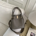 Detail of grey-brown bucket bag with gold hardware and geometric knit strap - Gray