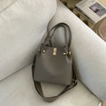 Detail der taupefarbenen Beuteltasche auf dem Sofa mit Webgurt und Goldnieten - Grau