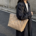 Sac cabas beige matelassé avec bandoulière chaîne porté par un mannequin en trench noir - Khaki
