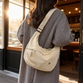 Bolso bandolera de nailon beige en forma de media luna con correa ajustable sobre abrigo - Blanco Roto