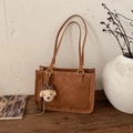 Detail of dark brown leather shoulder bag with woven handles and a cute bear charm - Brown