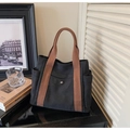 Detail of a black canvas tote bag with brown woven handles and metal magnetic snap buckle - Black