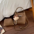 Détail du sac seau marron avec texture litchi, fermoir métal et pendentif ours - Marron (Avec Pendentif)