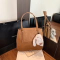 Detail view of a vintage brown leather bucket bag featuring a white plush rabbit charm - With Charm / Brown