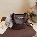 Close-up of dark brown lychee grain leather bucket bag with metal lock and plush rabbit charm - With Charm / Brown