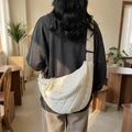 Sac bandoulière blanc matelassé en forme de croissant porté par un mannequin - Blanc