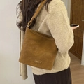 Detail of caramel brown suede bucket bag featuring golden hardware and embossed brand tag - Camel Brown