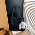 Detail of black tote bag featuring white contrast stitching and a plush bunny charm - With Charm / Black