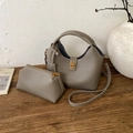 Grey pebbled leather bucket bag set with matching zipper pouch on a wooden table - Gray