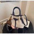 Detail of color-block canvas handbag featuring navy leather handles and gold metal buckles - With Charm / Blue