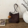 Detail of dark brown suede bucket bag with plush teddy charm on rustic wooden surface - Coffee with Pendant