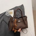 Minimalist dark brown handbag with bead charm and crossbody strap in a cozy setup - Coffee with Pendant