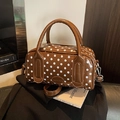 Bolso Boston marrón con lunares blancos y herrajes plateados sobre revista - Marrón