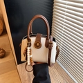 Borsa a conchiglia bianca con manici marroni e chiusura dorata retrò tenuta in mano - Bianco Sporco