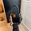 Borsa a conchiglia retrò nera lucida con charm in legno e chiusura dorata - Nero