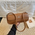 Bolso baguette de cuero marrón con logo plateado sobre una alfombra de paja tejida - Marrón