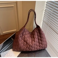 Close-up of burgundy quilted tote bag with silver snap button on a wooden office desk - Coffee