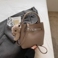 Détail du sac seau en cuir beige avec fermoir argenté et breloque lapin en peluche - Avec Pendentif / Gris