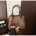 Détails d'un sac seau marron vintage avec pendentif ours et poignées robustes - Café avec Pendentif